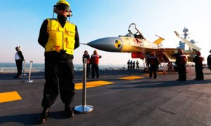 Ground crew check a J-15 fighter jet on China's first aircraft carrier, the Liaoning.